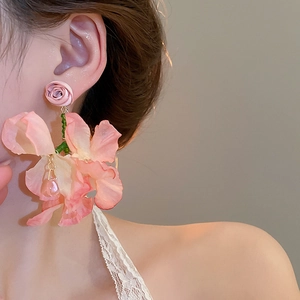 Detail of pink fabric flower tassel earring worn by a model in a natural soft light setting