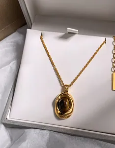 Detail of tiger eye stone pendant with gold irregular frame and twisted chain in box