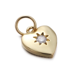 Macro shot of gold heart pendant featuring a starburst cut zircon on white background