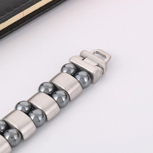 Macro detail of men's double-row hematite beads and brushed stainless steel link clasp