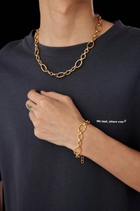 Close-up of matte gold chunky link chain necklace and bracelet on a dark gray shirt