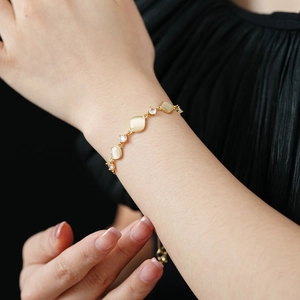 Nahaufnahme eines goldenen Rautenarmbands mit Katzenaugenstein und Zirkon am Handgelenk