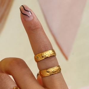Detailed macro shot of two gold star and moon relief rings with matte finish on finger