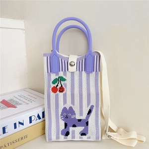 Detail of knitted tote bag with purple cat and red cherry patterns and silver magnetic clasp