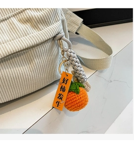 Detail of corduroy texture on small backpack with handmade orange charm and tag