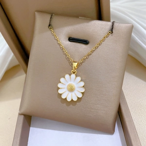 Close-up of a gold daisy pendant with white enamel petals on a fine titanium steel chain