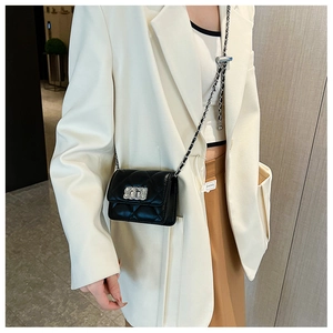 Close-up of black quilted mini square bag with silver chain strap worn by a model