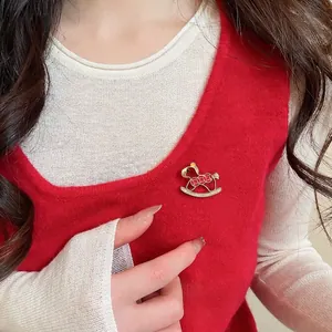 Elegant red rocking horse brooch with gold trim and rhinestones on a knitted sweater