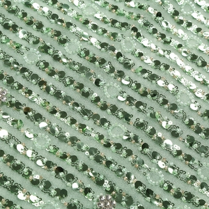 Detail of green sequins and bead embroidery with floral rhinestone on the dress fabric