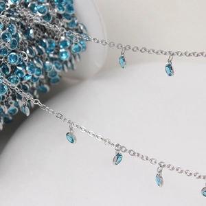 Macro detail of silver DIY chain with small blue crystal round pendants for jewelry making