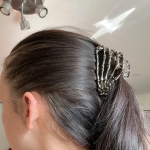 Dettaglio del fermaglio per capelli a mano di scheletro in metallo argento indossato