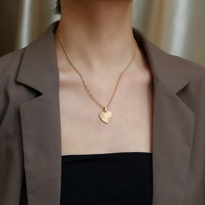 Close-up of golden sunburst heart pendant necklace worn on a woman's neck