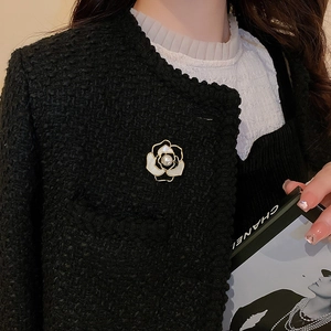 Détail de broche fleur camélia avec perle sur une veste en tweed au style élégant et chic
