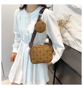Detail view of brown crossbody camera bag with monogram pattern and matching small round pouch