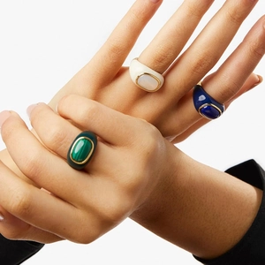Close-up of three 18k gold plated rings with malachite, white shell and blue enamel on model