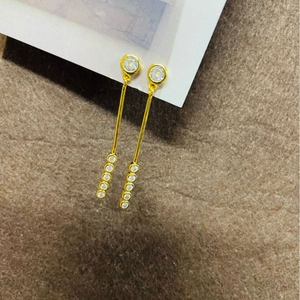 Boucles d'oreilles pendantes dorées avec cristaux verticaux sur fond en peluche