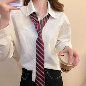 Detail of red and black striped tie paired with a white shirt and denim jeans