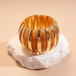 Detail of amber acrylic beads and gold polished metal spacers on an elastic bracelet