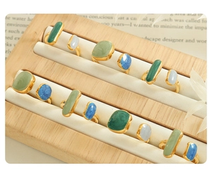 Detail of adjustable gold-plated enamel rings with colorful stones in a wooden tray
