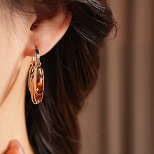 Gros plan de boucles d'oreilles vintage en verre ambré et créoles dorées sur modèle
