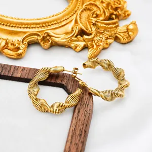 Detail of gold spiral spring earrings with wire-wrapped design on white silk fabric
