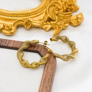 Detail of gold spiral spring earrings with wire-wrapped design on white silk fabric