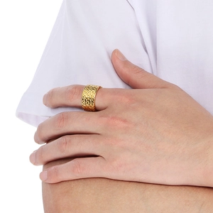 Detail shot of a wide gold-colored ring with textured woven patterns and retro punk style