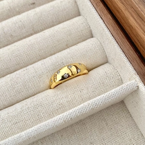 Macro detail of gold star ring with cubic zirconia inlay on beige jewelry box slot