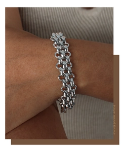 Detailed close-up of a chunky silver metal OT buckle bracelet worn on a model's wrist