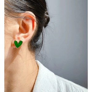 Elegant green heart earrings with gold trim worn by a model in a minimalist style