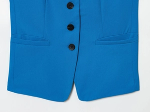 Détail de trois boutons noirs, poches passepoilées et ourlet sur blazer bleu éclatant