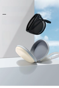 Detail of portable foldable sunglasses with round black lenses and compact storage case