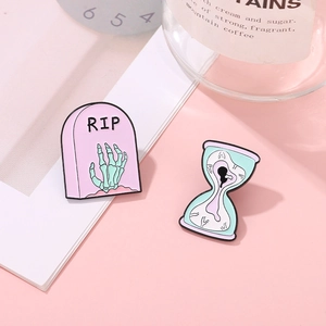 Creepy cute enamel pin set with pink RIP tombstone and surreal eyeball hourglass