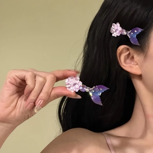 Detailed view of a purple flower and mermaid tail hair clip with pearls on a model