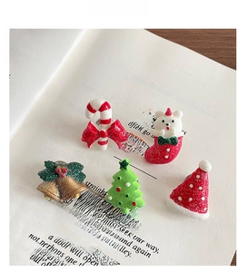 Detailed view of resin Christmas charms including tree and bear on open book pages