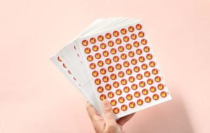 Close-up of hand holding stack of red reward stickers with yellow thumbs-up icon