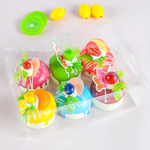 Set of six colorful artificial cupcakes with fruit toppings in transparent packaging box
