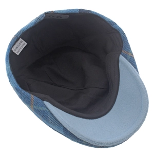 Detail view of the interior black lining and polyester fabric label of a plaid beret