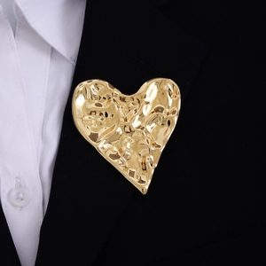 Close-up of golden vintage textured heart brooch pinned on a black suit lapel
