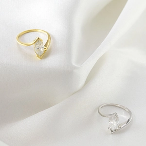 Elegant 18k gold and silver rings with marquise cut moissanite on white silk fabric