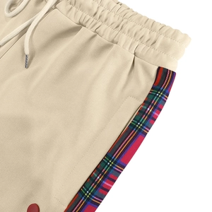 Detail of beige joggers featuring drawstring elastic waist and colorful plaid side stripes