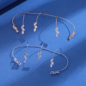Dettaglio di ear cuff in oro e argento con zirconi marquise su una superficie scura ruvida
