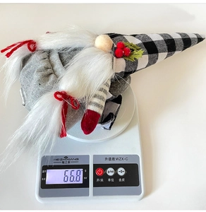 Christmas gnome doll with plaid hat and white beard weighed on an electronic scale at 66.8g