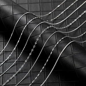 Detail view of various silver-colored chain styles on a black leather display stand