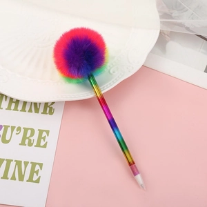 Close-up of cute plush pompom pen with rainbow gradient barrel on a pink desktop