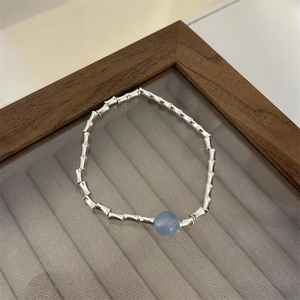Detailed shot of a silver bamboo joint bracelet with a central light blue bead
