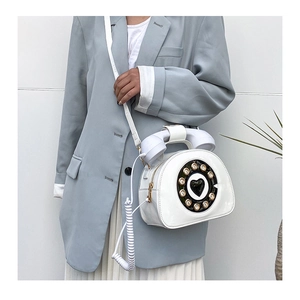Detail of white vintage telephone-shaped crossbody bag with retro dial and glossy finish