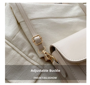 Detail of a cream shoulder bag showing the gold adjustable buckle and leather texture