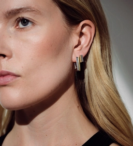 Gros plan de boucles d'oreilles géométriques bicolores portées par un mannequin