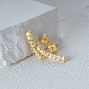 Macro shot of gold-plated curved stud earrings with inlaid zircon and 925 silver hallmark